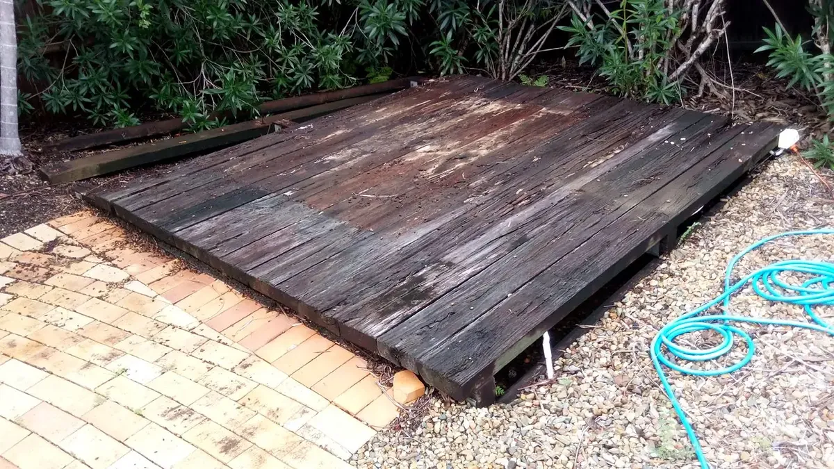a weathered grey timber deck with split and cupped boards before restoration